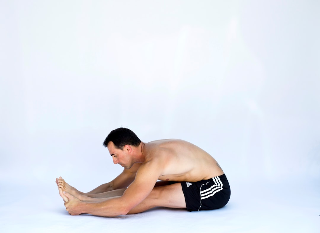 a shirtless man sitting on the ground with his legs crossed