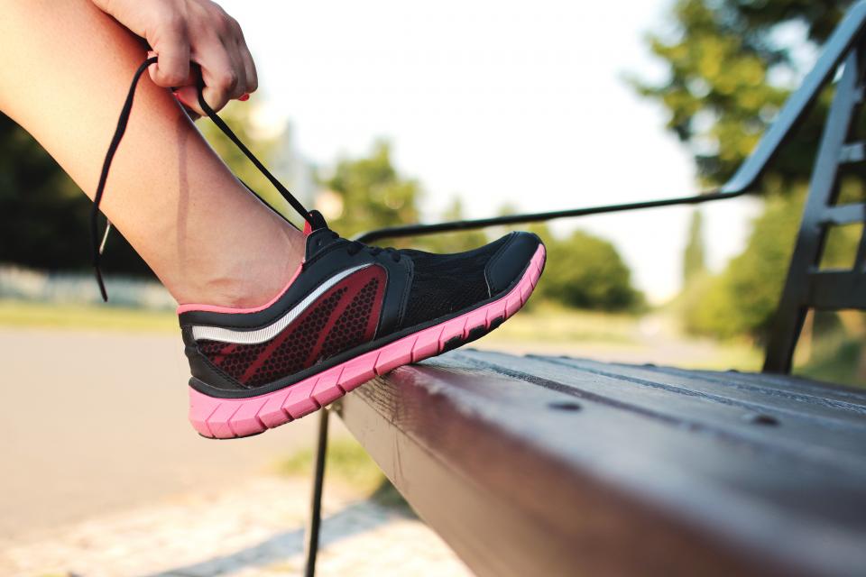 Paire de chaussures de sport posée près d'une porte d'entrée à côté d'un sac fermé