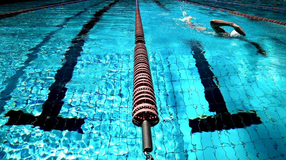 Ligne d'eau d'une piscine couverte avec un nageur progressant lentement en crawl