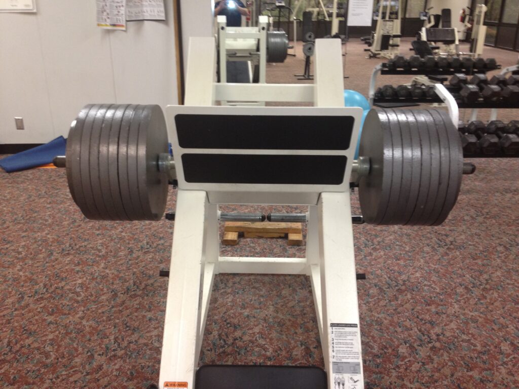 Presse à cuisses inclinée chargée de disques dans une salle de musculation vide