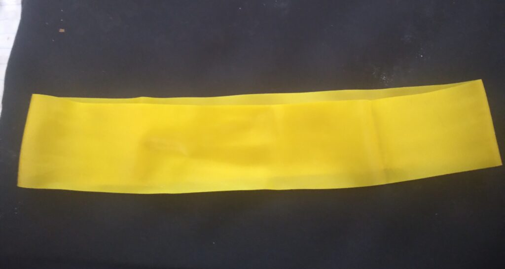 Bande élastique de couleur posée au sol à côté d'un tapis roulé dans une pièce claire