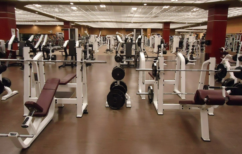 Rangée de tapis de course vides dans une salle de sport éclairée le soir