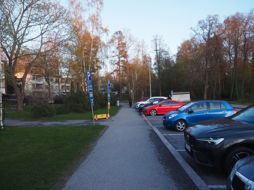 Parking éclairé en fin de journée avec quelques voitures garées devant un bâtiment