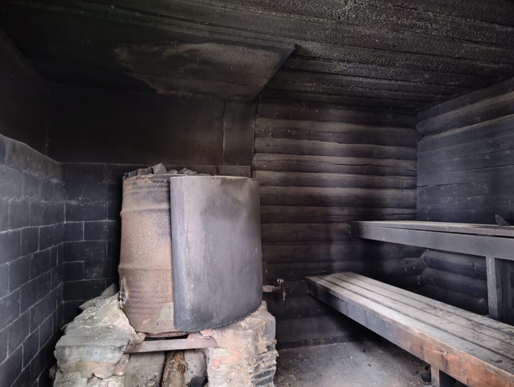 Int&eacute;rieur d'un sauna en bois avec des bancs vides et un po&ecirc;le &agrave; pierres chaudes