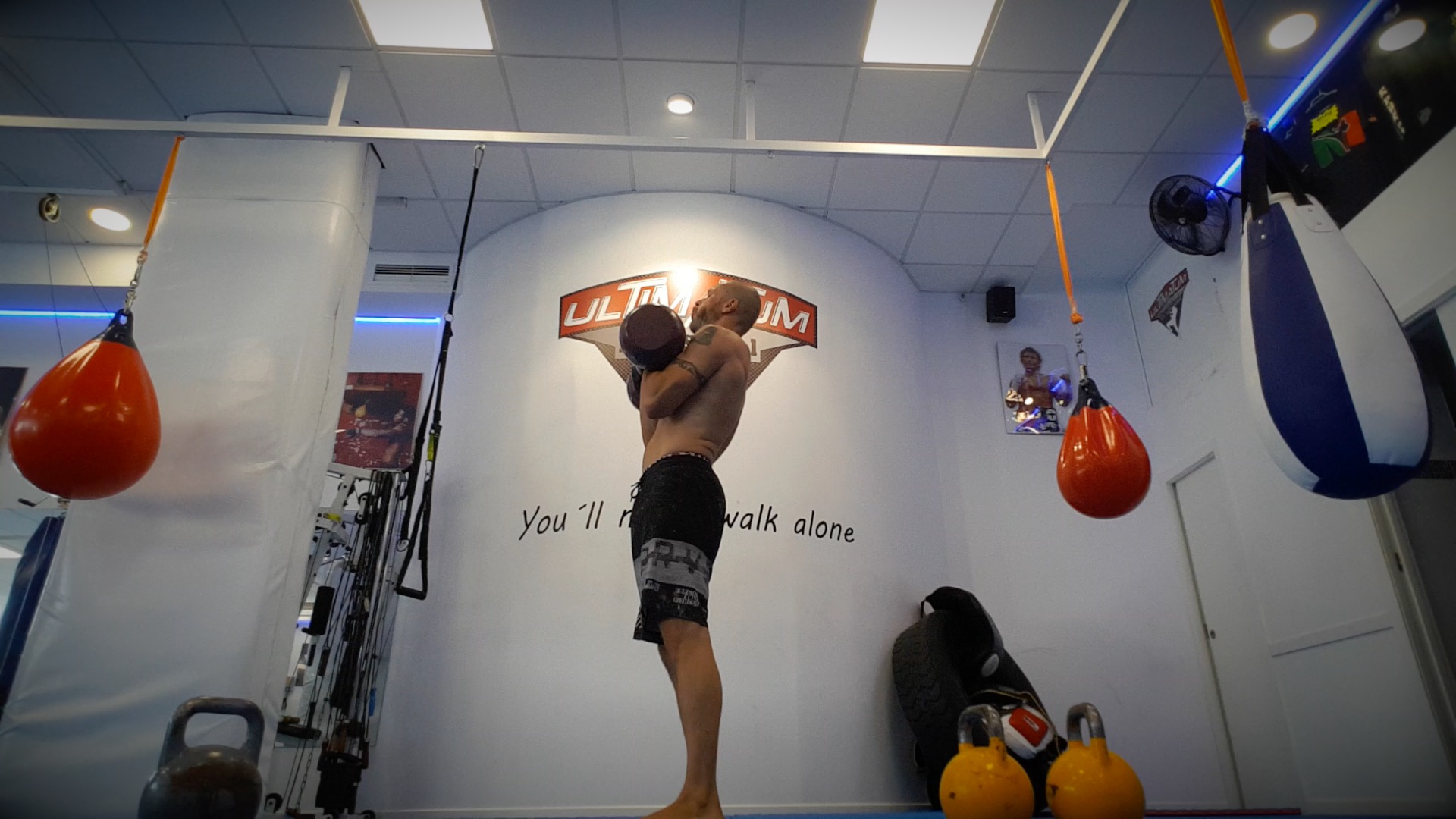 Rangée de kettlebells de tailles croissantes alignées sur un râtelier bas en salle