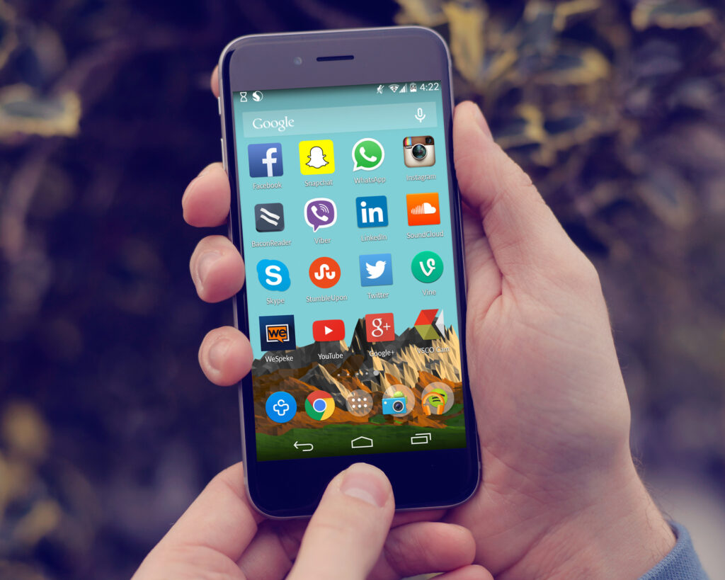 T&eacute;l&eacute;phone affichant plusieurs ic&ocirc;nes de r&eacute;seaux sociaux pos&eacute; sur une table en bois