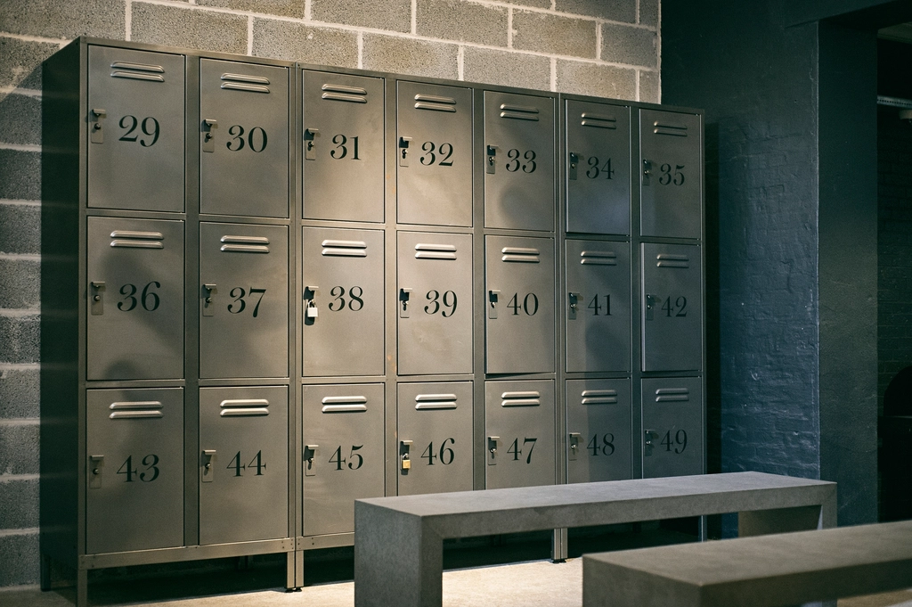 Vestiaire de salle de sport désert avec banc en bois et casiers métalliques fermés